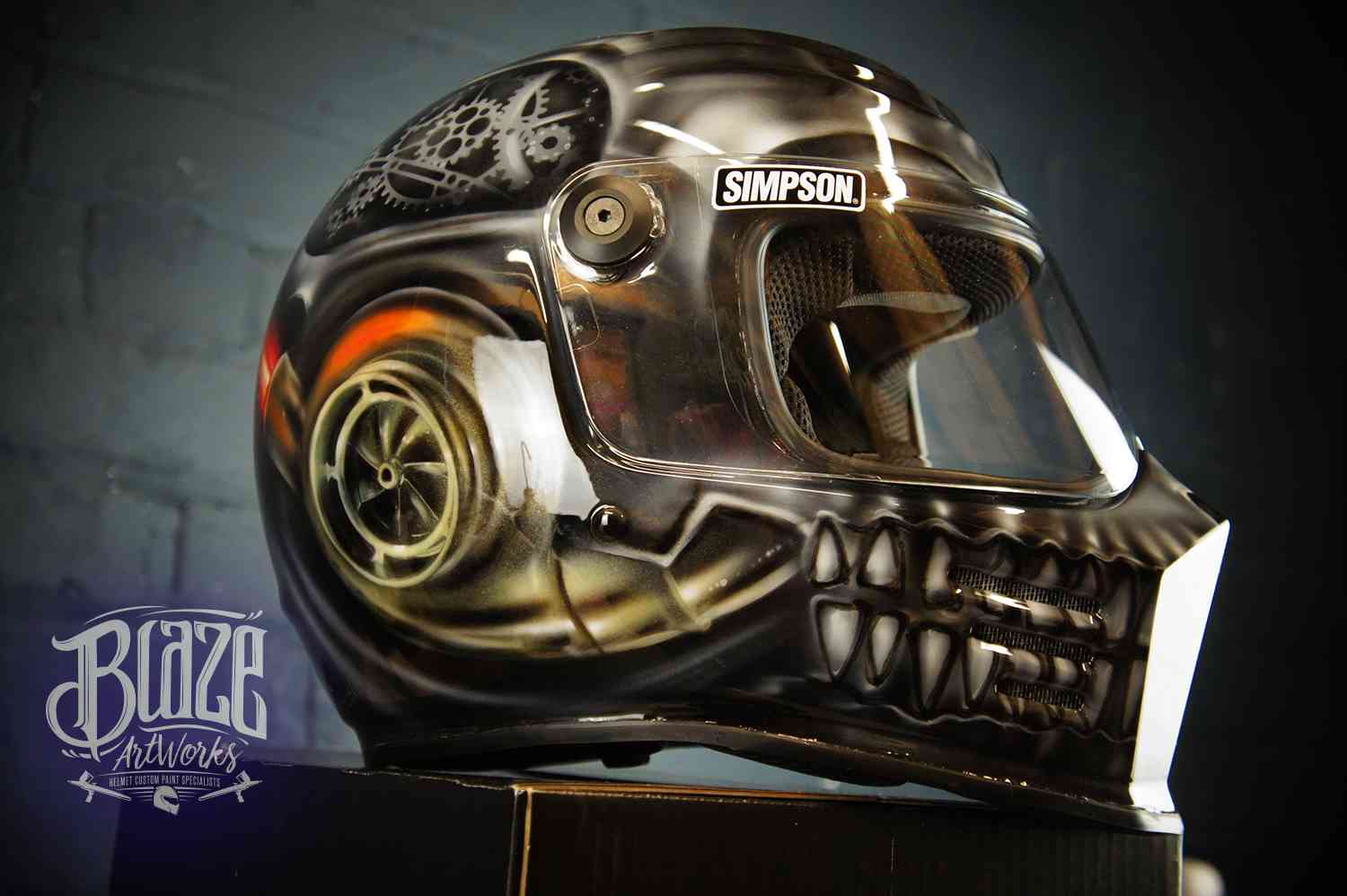 Steampunk skull motorcycle helmet with bronze metallic gears, mechanical jaw teeth, and industrial design elements on black base